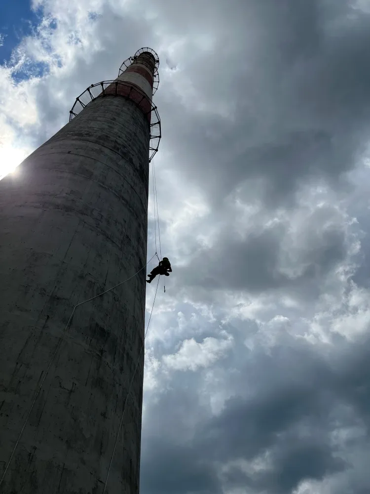 Zdjęcie przedstawia alpinistę przemysłowego podczas pracy na wysokości.